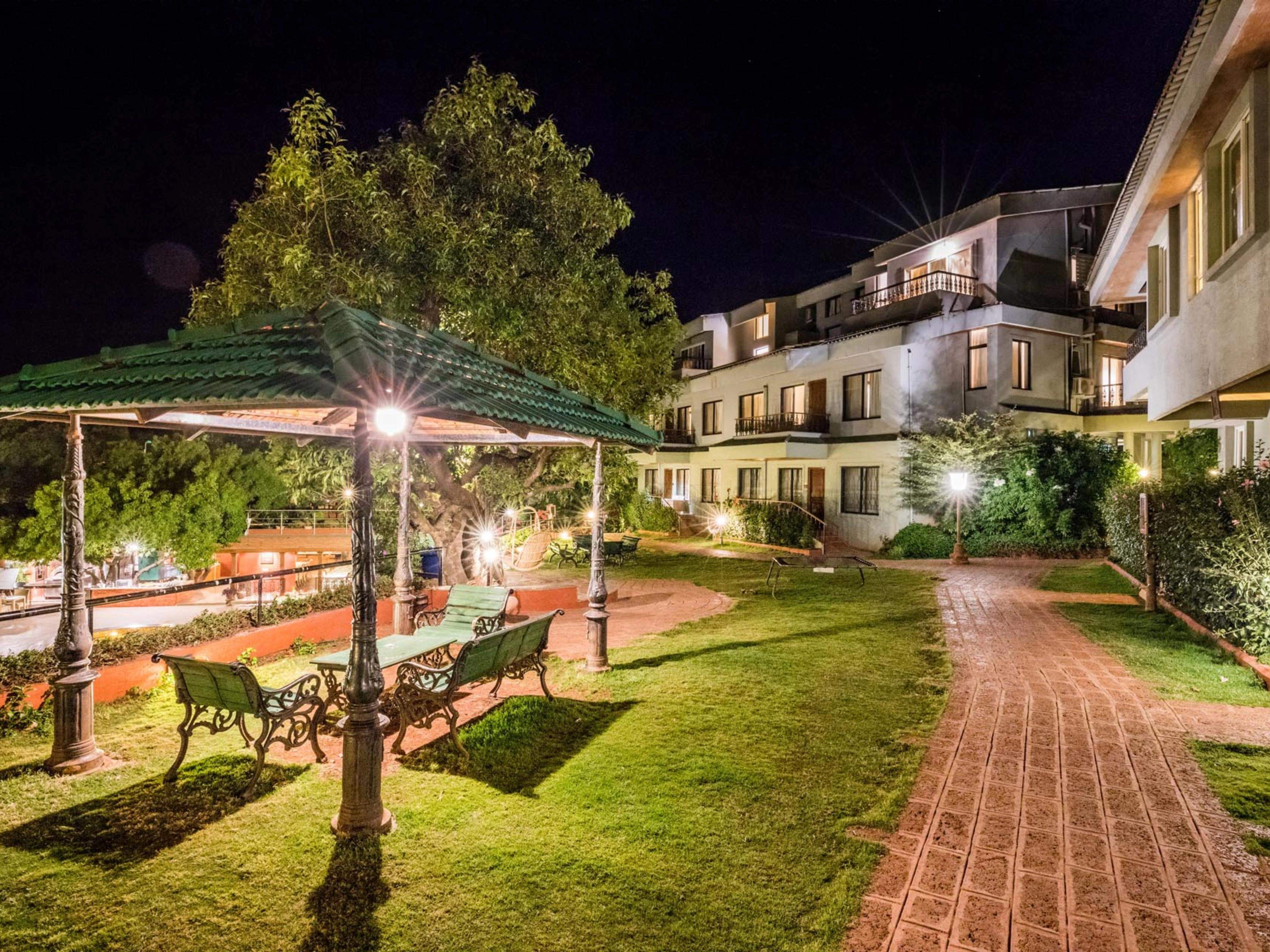 Beautifully lit resort garden path with a gazebo and seating area at Ramsukh Resort.